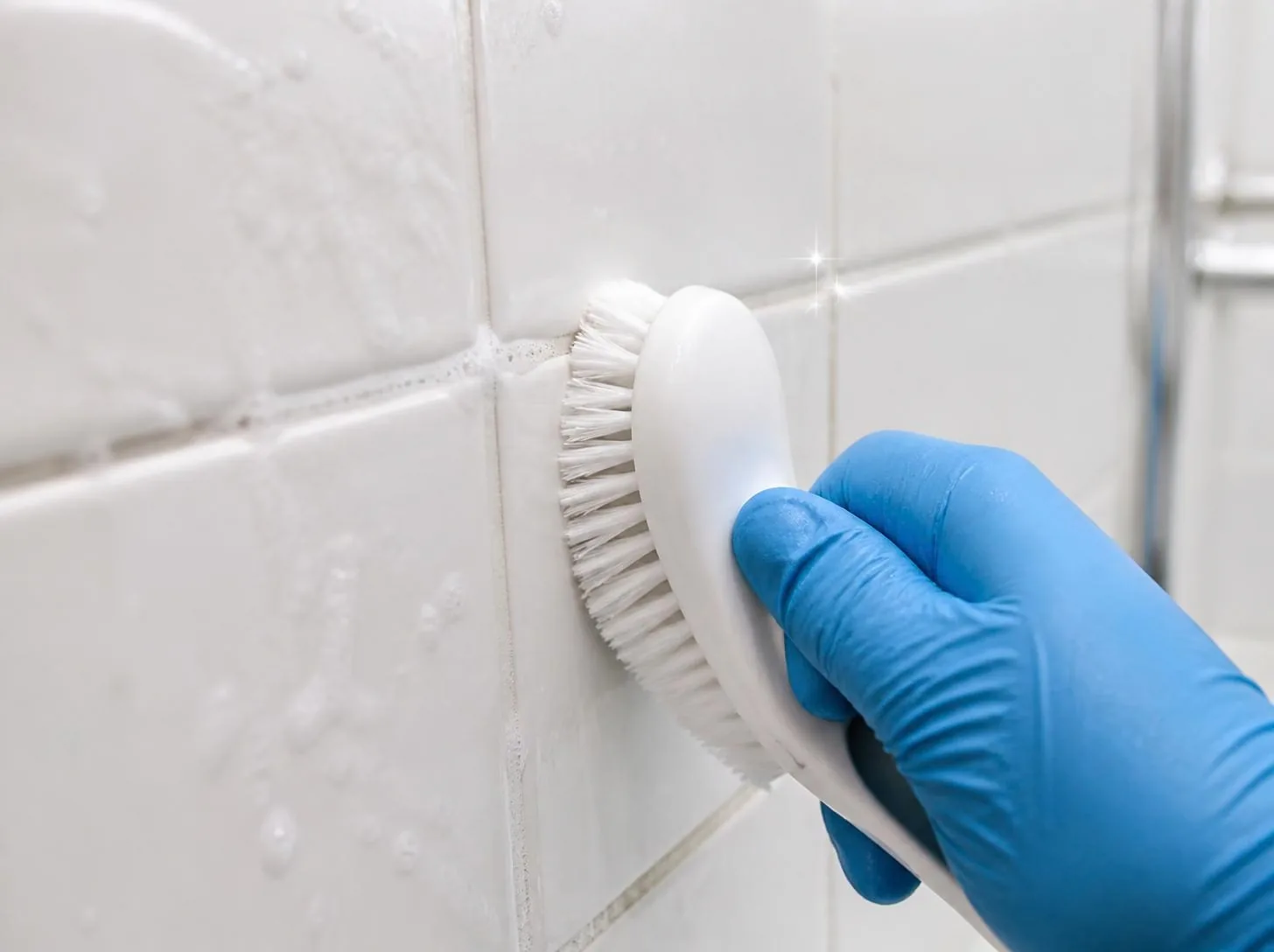 Gloved hand wiping sparkling clean white bathroom tiles
